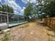 Backyard view featuring a screened-in pool, shed, and wood fence under a partly cloudy sky at 12801 College Hill Dr, Hudson, FL 34667