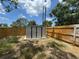 Backyard shed featuring grey paint, a black door, and a small concrete patio at 12801 College Hill Dr, Hudson, FL 34667