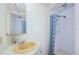Well-lit bathroom features a vanity with a beige sink and a shower with a blue patterned curtain at 144 Melody Ln, Tarpon Springs, FL 34689