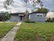 Charming single-story home with gray siding, a red front door and a small, partially-overgrown front yard at 1902 W Aileen St, Tampa, FL 33607