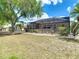 View of the home's screened-in lanai and back yard with mature trees and landscaping at 2018 E Del Webb Blvd, Sun City Center, FL 33573