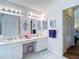 Bright bathroom featuring dual sinks with white cabinetry, decorative mirrors, and neutral flooring at 2018 E Del Webb Blvd, Sun City Center, FL 33573