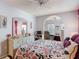 A comfortable bedroom features an arched entrance, ceiling fan, and floral comforter at 2018 E Del Webb Blvd, Sun City Center, FL 33573