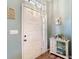 Bright foyer with decorative cabinet, light blue walls, white trim, and a front door with glass panels at 2018 E Del Webb Blvd, Sun City Center, FL 33573