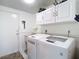 Bright laundry room with white cabinets, modern washer and dryer, and convenient access to the outside at 2018 E Del Webb Blvd, Sun City Center, FL 33573