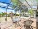 Spacious, screened-in patio with brick flooring, spa, outdoor seating, and serene backyard views at 2018 E Del Webb Blvd, Sun City Center, FL 33573