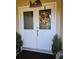 Inviting front door with decorative wreath and 'Peace on Earth' sign, flanked by potted plants at 2704 E Montague E Ct, Clearwater, FL 33761