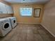 Bright laundry room with tile flooring, window, laundry machines and overhead storage at 2704 E Montague E Ct, Clearwater, FL 33761