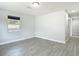 Bright bedroom with gray wood-look tile, white walls, and natural light from a window at 3020 E Louisiana Ave, Tampa, FL 33610