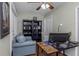 Cozy office with a sofa, two black bookshelves, a ceiling fan with lights, and a wooden desk at 403 Saint Petersburg W Dr, Oldsmar, FL 34677