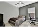 This bedroom features a ceiling fan, light gray walls, a bed with gray pillows and a black desk with an executive chair at 4224 Crayford Ct, Land O Lakes, FL 34638