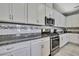 Stylish kitchen with granite countertops, stainless steel appliances, white cabinetry, and mosaic tile backsplash at 4224 Crayford Ct, Land O Lakes, FL 34638