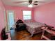 Pink bedroom featuring wood floors, a bed with a colorful comforter, and a door to the outside at 4702 Cypress Serenity Dr, Plant City, FL 33565