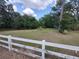 Expansive front yard with a white fence, mature trees, and a lush green lawn at 4702 Cypress Serenity Dr, Plant City, FL 33565
