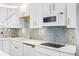 Modern kitchen with white cabinets, updated appliances, and stylish backsplash at 4740 Beach Se Dr # A, St Petersburg, FL 33705