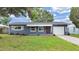 Charming one-story home with blue exterior, awning, red door, manicured lawn and single car garage at 5772 4Th N Ave, St Petersburg, FL 33710
