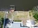 Waterfront property with boat lift, minimal landscaping, shed, and small patio with an AC unit at 5812 Liverpool Dr, Tampa, FL 33615