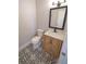 This bathroom features a toilet, wood vanity, black and white patterned floors, and framed mirror at 5812 Liverpool Dr, Tampa, FL 33615