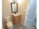 This bathroom features a toilet, wood vanity, black and white patterned floors, and framed mirror at 5812 Liverpool Dr, Tampa, FL 33615