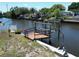Waterfront property featuring a wooden boat lift on a canal with homes in the background at 5812 Liverpool Dr, Tampa, FL 33615