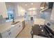 Modern kitchen with stainless appliances, white cabinets, and open layout to the wine bar at 5812 Liverpool Dr, Tampa, FL 33615