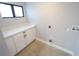 Well-lit laundry room featuring a window, white cabinets and quartz countertops at 5812 Liverpool Dr, Tampa, FL 33615