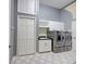 Modern laundry room featuring gray cabinets and stainless steel washer and dryer at 7333 Royal Oak Dr, Spring Hill, FL 34607