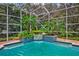 Screen-enclosed pool area with lush tropical landscaping and calming water feature at 7333 Royal Oak Dr, Spring Hill, FL 34607