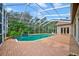 Enclosed pool area with brick paver patio and lush tropical landscaping at 7333 Royal Oak Dr, Spring Hill, FL 34607