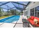 Relaxing screened-in pool area with an inviting red sofa and a bench, perfect for outdoor lounging at 742 45Th Ne Ave, St Petersburg, FL 33703