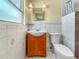 Bathroom featuring tiled walls, a white sink and toilet, wood vanity, a mirror, and lighting at 8210 68Th N Way, Pinellas Park, FL 33781