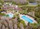 Aerial view of the community clubhouse with pools, landscaping, and palm trees, set next to a pond at 8219 Summer Brook Ct, Land O Lakes, FL 34638