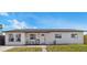 Single-story home featuring a tidy front lawn, welcoming porch chairs, and modern windows at 8240 Jacaranda Ave, Seminole, FL 33777