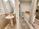 Stylish half-bathroom features a pedestal sink, oval mirror, and tiled walls with a modern aesthetic at 11246 Kapok Grand Cir, Madeira Beach, FL 33708