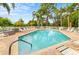 Community pool surrounded by lounge chairs, landscaping, and fenced perimeter at 11246 Kapok Grand Cir, Madeira Beach, FL 33708