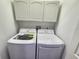A laundry room showcasing a white washer and dryer set with white cabinets above at 11246 Kapok Grand Cir, Madeira Beach, FL 33708