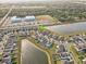 An aerial photograph of a residential area with a lake, community center and sports fields surrounded by lush greenery at 11476 Sage Canyon Dr, Riverview, FL 33578