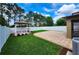 A fenced backyard offers a gazebo, green grass, a patio and some pine trees at 12499 Longstone Ct, New Port Richey, FL 34655