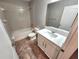 A well-lit bathroom featuring tile floors, shower-tub, a vanity with a sink and a large mirror at 12499 Longstone Ct, New Port Richey, FL 34655