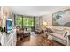 Bright living room with hardwood floors, art, and view to outside at 14130 Rosemary Ln # 1202, Largo, FL 33774