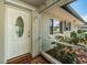 Charming front porch featuring a decorative glass door, tiled flooring, and vibrant surrounding greenery at 1622 Elizabeth Ln, Clearwater, FL 33755
