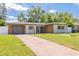 Charming single-story home featuring a manicured lawn and a long driveway to the attached garage at 1717 Thames St, Clearwater, FL 33755