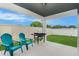 Covered back patio featuring teal chairs, a grill, and a well-maintained lawn at 20659 Drake Elm Dr, Land O Lakes, FL 34638