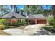 Charming single-story home with brick accents, dormer windows, mature landscaping, and an attached two-car garage at 213 Sheffield E Cir, Palm Harbor, FL 34683