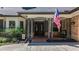 Inviting entrance with double doors, sidelights, covered porch, mature landscape, and an American flag at 213 Sheffield E Cir, Palm Harbor, FL 34683