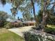 Charming home featuring a manicured lawn, mature trees, and a circular driveway at 213 Sheffield E Cir, Palm Harbor, FL 34683