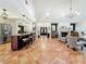 Open living space features the kitchen with seating, fireplace, tile flooring, and access to foyer at 213 Sheffield E Cir, Palm Harbor, FL 34683