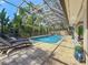 Screened pool and patio area with lounge chairs creating an ideal space for relaxation and enjoyment at 213 Sheffield E Cir, Palm Harbor, FL 34683