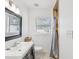 Modern bathroom with stylish vanity, black framed mirror, and a tiled shower with curtain at 232 Emerald Ln, Largo, FL 33771