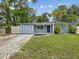 Charming single-story home with a blue exterior, well-maintained lawn, and lush trees at 232 Emerald Ln, Largo, FL 33771